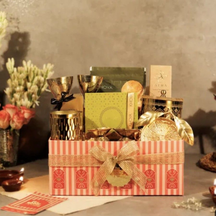 Festive & Diwali gifting: Festive Diwali gift hamper with gold brass diyas, glasses and candle jars in a pink striped gift box with a gold ribbon